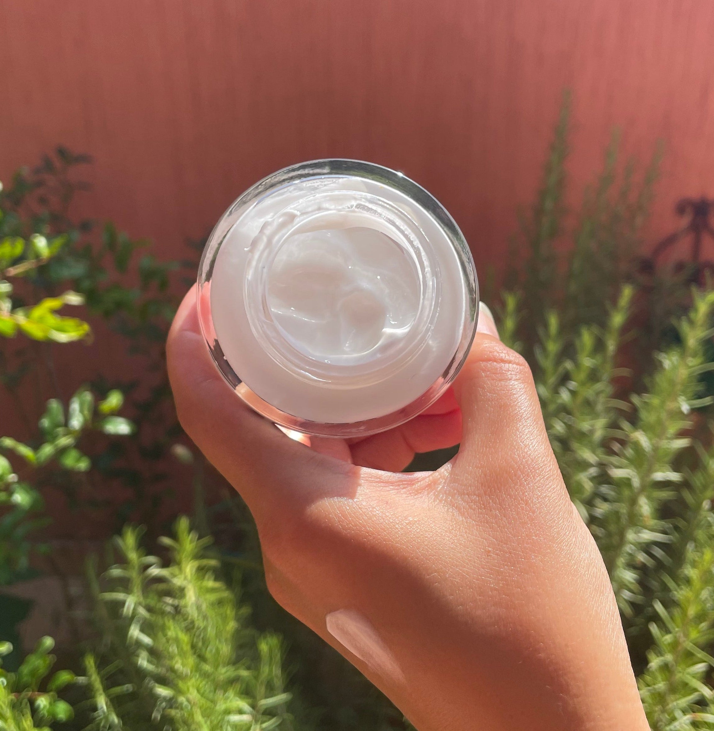 ZAYNA Desert Glow Day Cream in a glass jar held in hand, featuring a white hydrating formula with argan oil